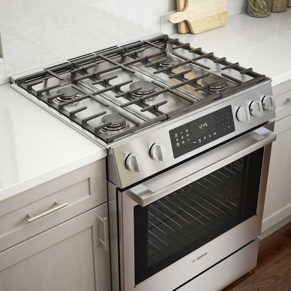 Stainless steel gas stove with oven in a kitchen setting